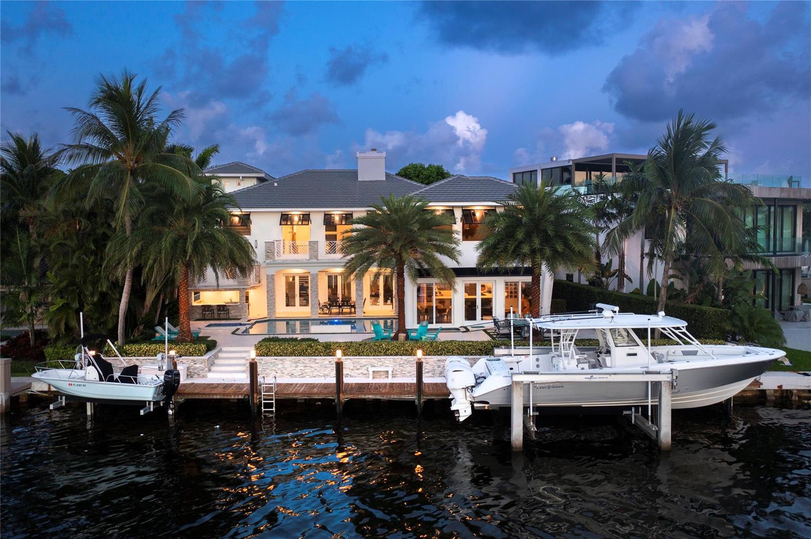 A two-story waterfront house with a pool, dock, and two boats at dusk — 2307 N Riverside Drive, Pompano Beach FL 33062, POMPANO BEACH, FL