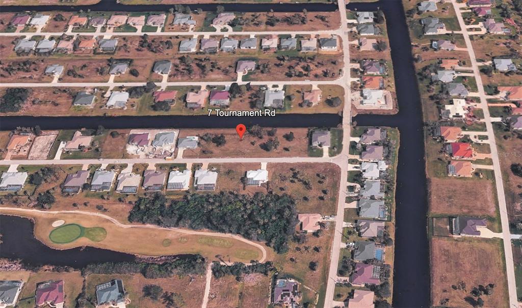 This aerial view shows a vacant residential lot situated along a canal in a neighborhood — 7 TOURNAMENT ROAD, ROTONDA WEST, FL