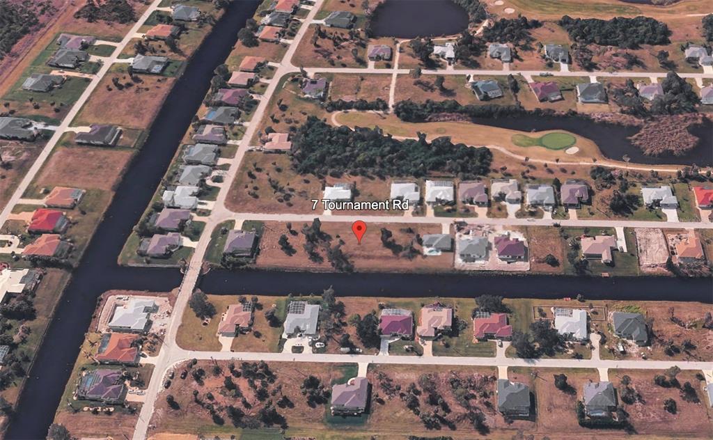 An aerial view shows a vacant residential lot situated between houses along a canal — 7 TOURNAMENT ROAD, ROTONDA WEST, FL