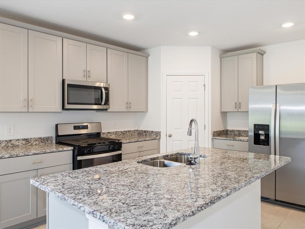 A kitchen with light gray cabinets, granite countertops, stainless steel appliances, and a central island — 2880 WILD OLIVE DRIVE, ST CLOUD, FL