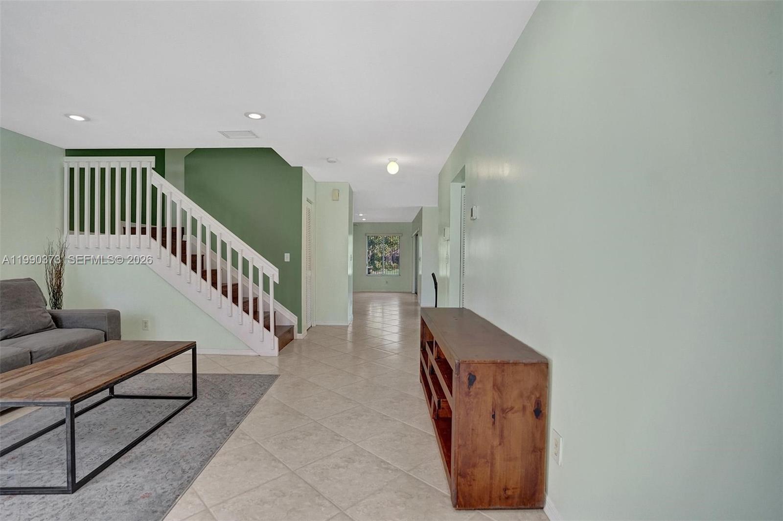 A living room features a staircase with white railings, tile flooring, and light green walls — 1726 SW 110th Ter, Davie FL 33324, DAVIE, FL