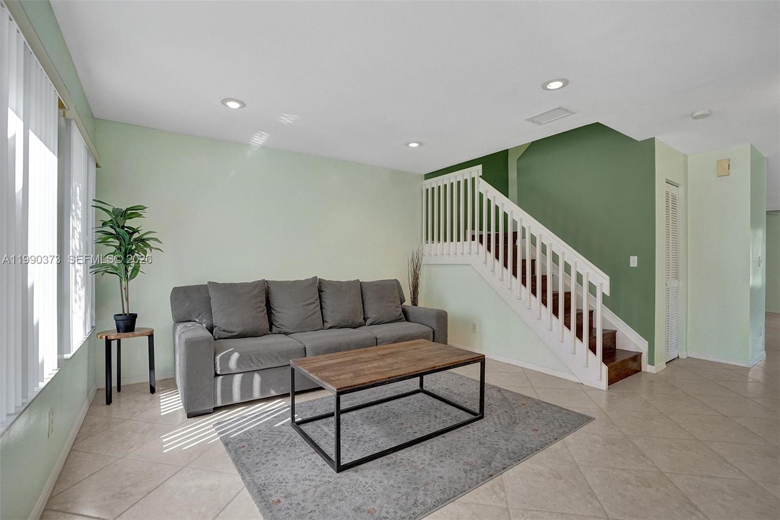 A living room features a gray sofa, a wooden coffee table, and a staircase — 1726 SW 110th Ter, Davie FL 33324, DAVIE, FL
