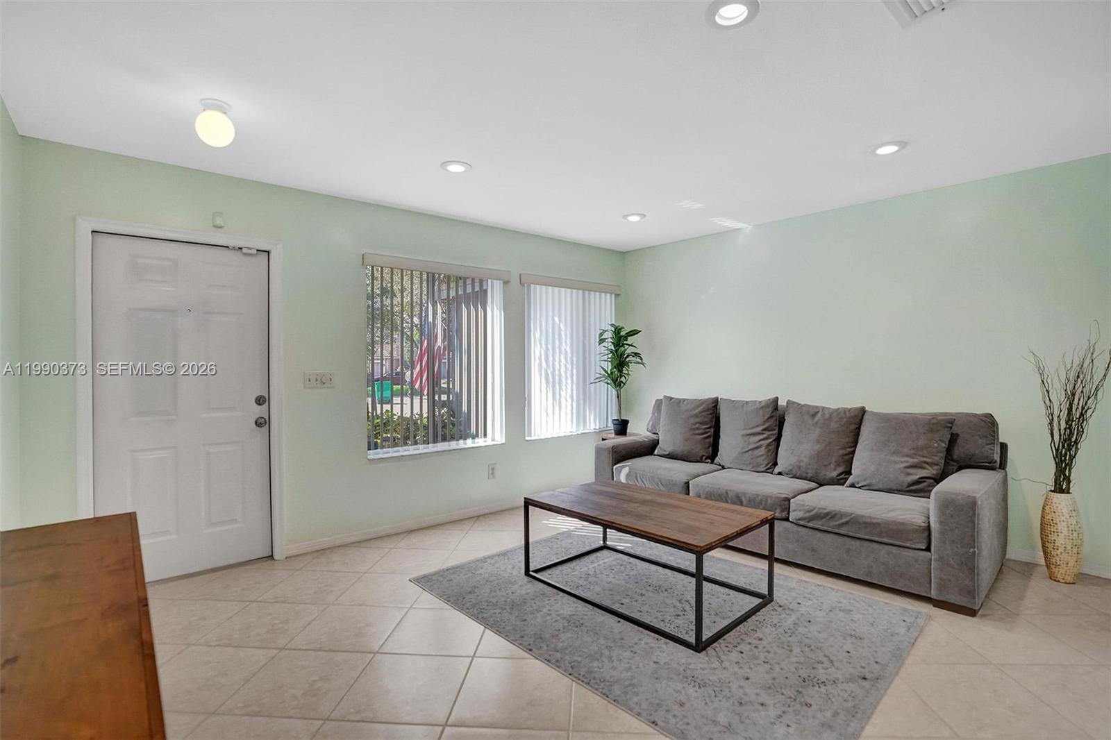 A living room features light green walls, tile flooring, a gray sofa, and a coffee table — 1726 SW 110th Ter, Davie FL 33324, DAVIE, FL