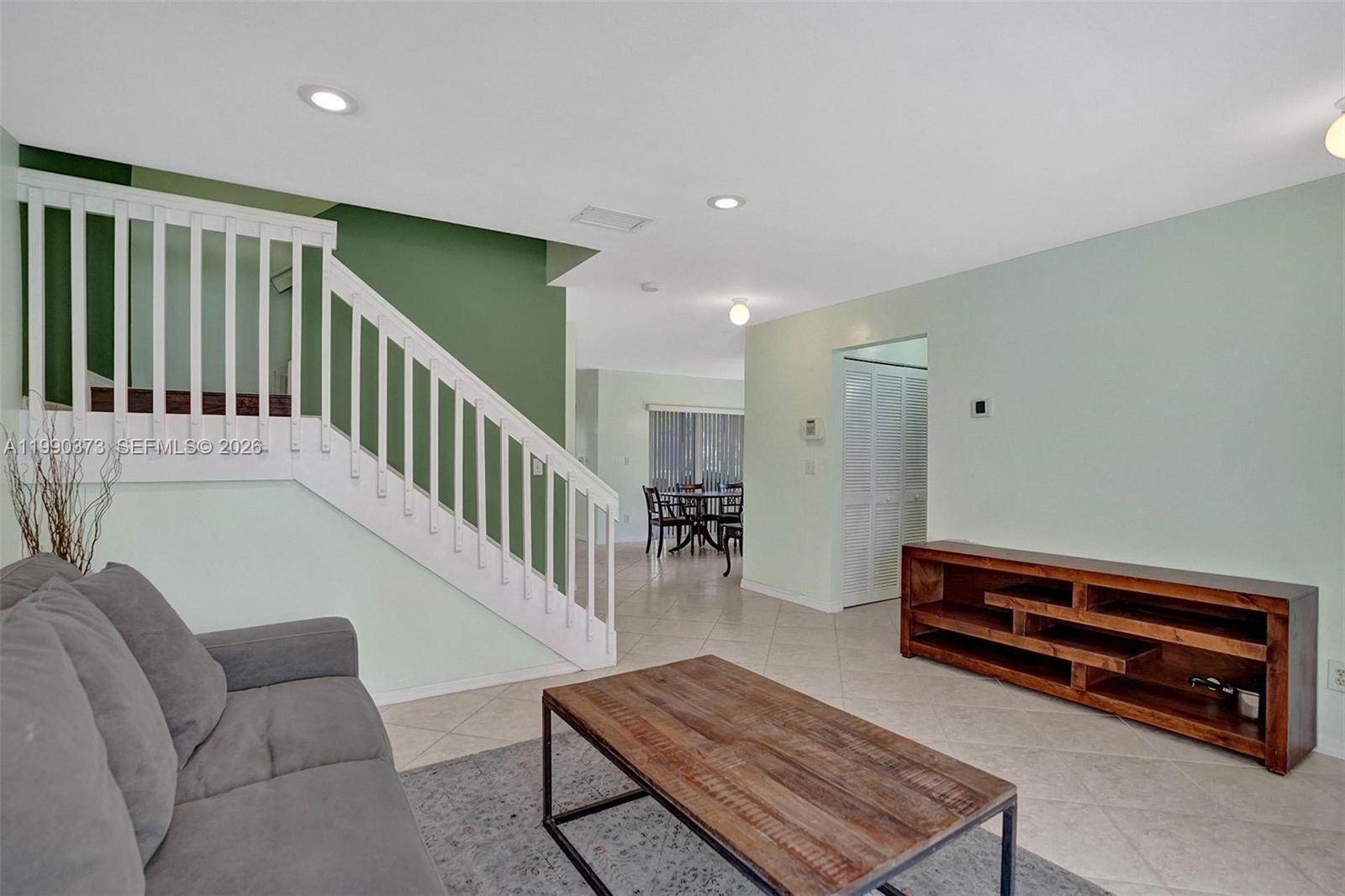 A living room features a wooden coffee table, a grey sofa, and a staircase — 1726 SW 110th Ter, Davie FL 33324, DAVIE, FL