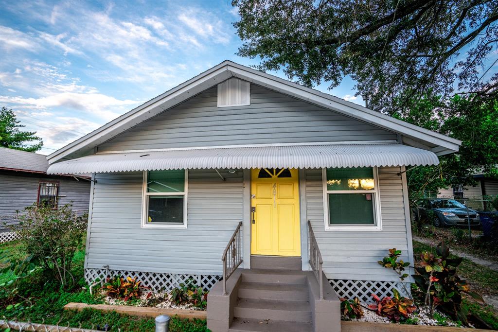 A gray house with a yellow front door, metal awning, and lattice skirting — 4811 N 30TH STREET, TAMPA, FL