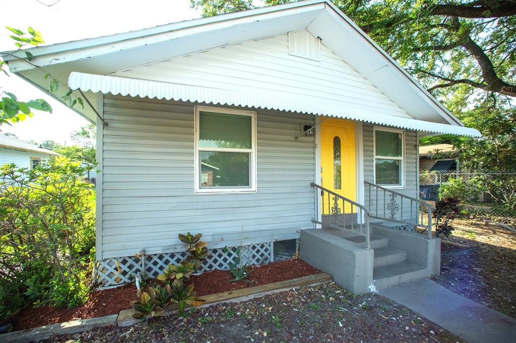 A small, light-gray house with a bright yellow front door and a white metal awning — 4811 N 30TH STREET, TAMPA, FL