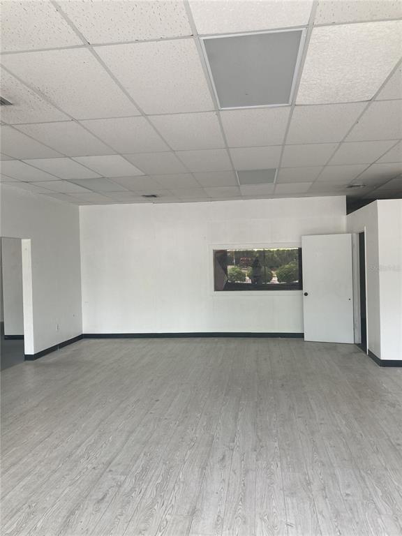 An empty commercial space features light wood-look flooring, white walls, and a drop ceiling — 2020 NW 6TH STREET, GAINESVILLE, FL