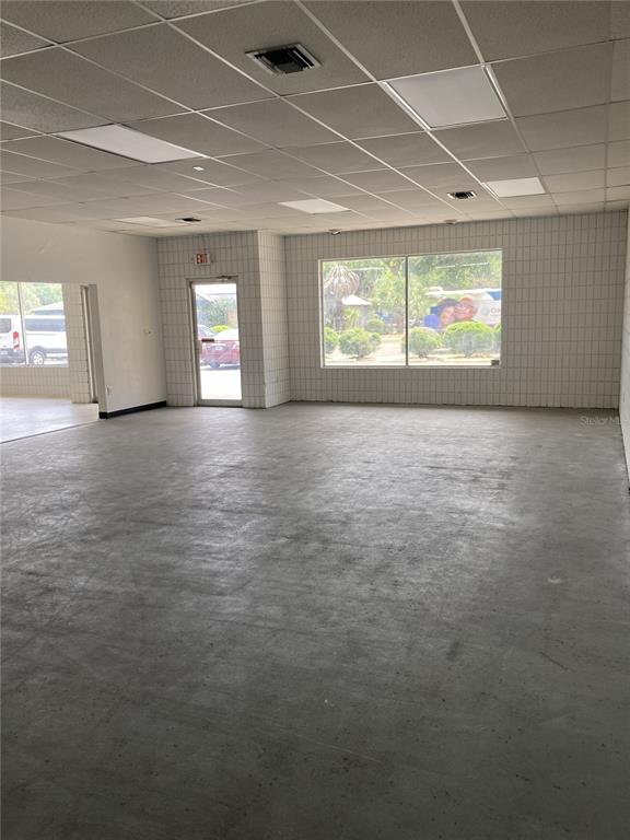 An empty commercial space features a drop ceiling, tiled walls, and a concrete floor — 2020 NW 6TH STREET, GAINESVILLE, FL