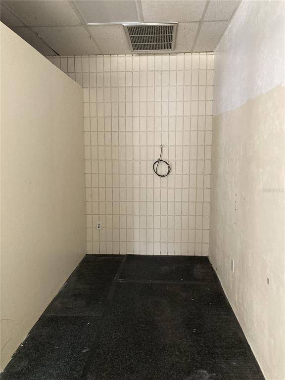 A small, narrow room features tiled back walls, a dark floor, and a ceiling vent — 2020 NW 6TH STREET, GAINESVILLE, FL