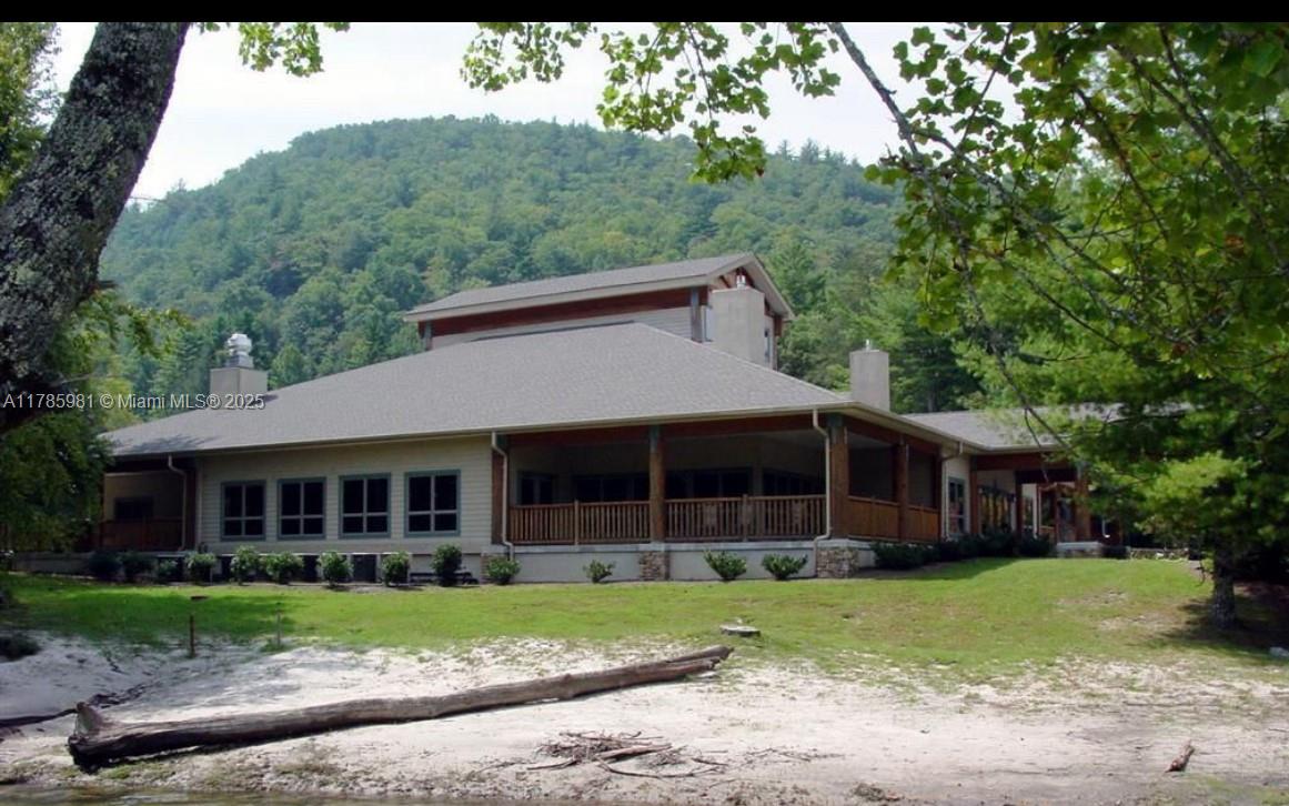A large, single-story house with a wrap-around porch sits on a sandy lakeshore — Lot 66 Juniper Court, NC 28774, NC