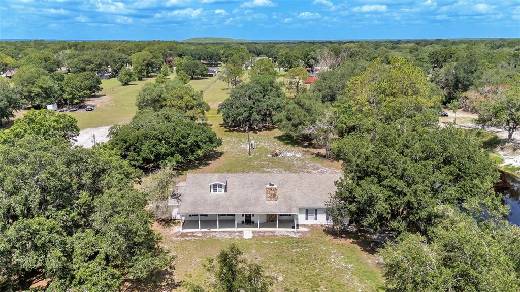 An aerial view shows a single-story house with a covered porch surrounded by trees — 29 LAKE ARROWHEAD DRIVE, WINTER HAVEN, FL