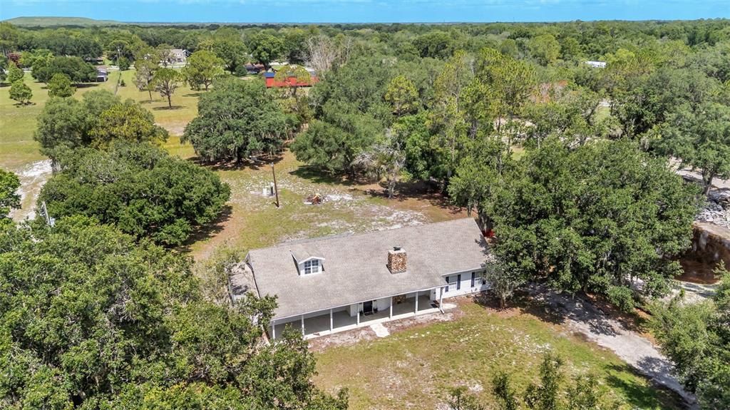 An aerial view shows a single-story house with a shingled roof surrounded by mature trees — 29 LAKE ARROWHEAD DRIVE, WINTER HAVEN, FL