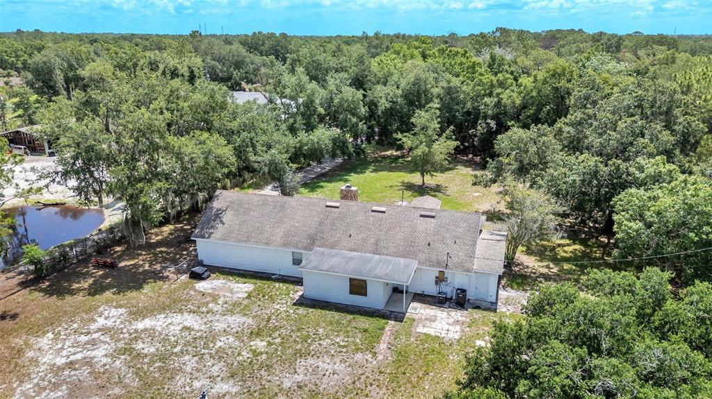 An aerial view of a white house with a shingled roof surrounded by trees — 29 LAKE ARROWHEAD DRIVE, WINTER HAVEN, FL