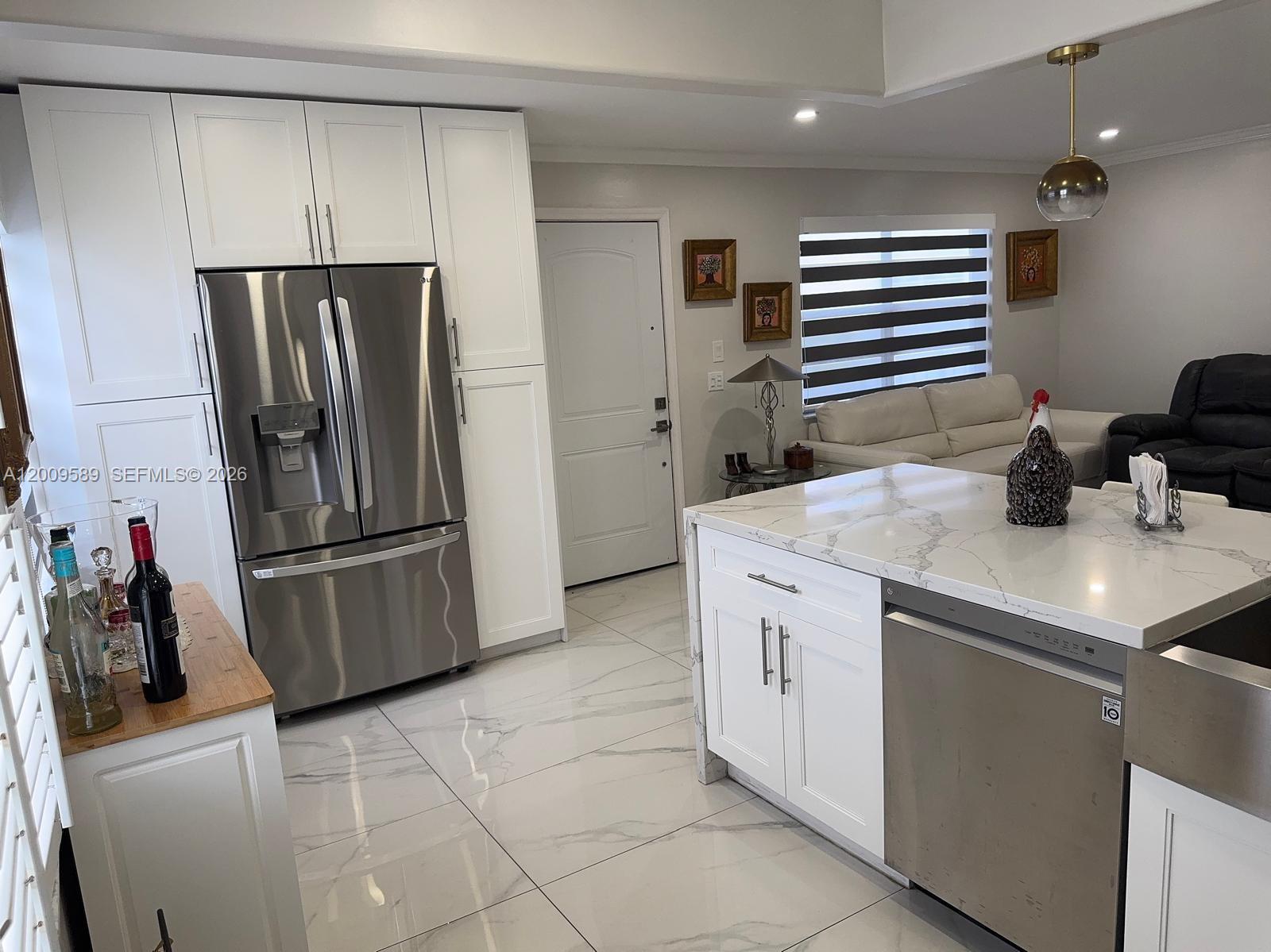 A kitchen features white cabinets, stainless steel appliances, a marble-topped island, and white tile flooring — 31 Normandy A # A, Delray Beach FL 33484, DELRAY BEACH, FL