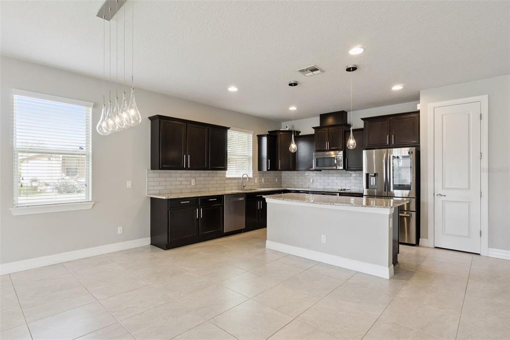 A kitchen with dark cabinets, granite countertops, a center island, and light tile flooring — 2651 TAHOE TERRACE, ST CLOUD, FL