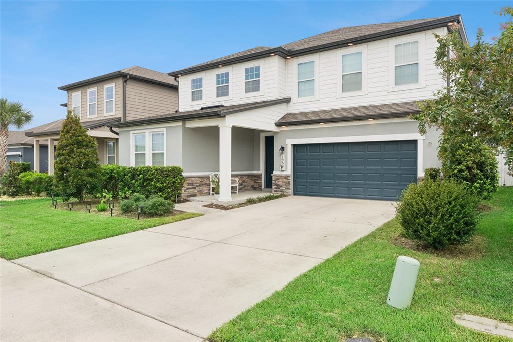 A two-story suburban house features a gray stucco and white siding exterior with a garage — 756 STEERVIEW STREET, ST CLOUD, FL