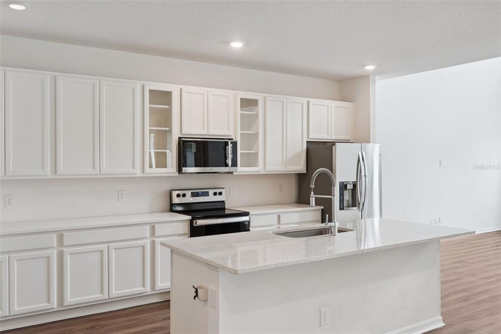 A kitchen with white cabinets, stainless steel appliances, and a central island with a sink — 756 STEERVIEW STREET, ST CLOUD, FL