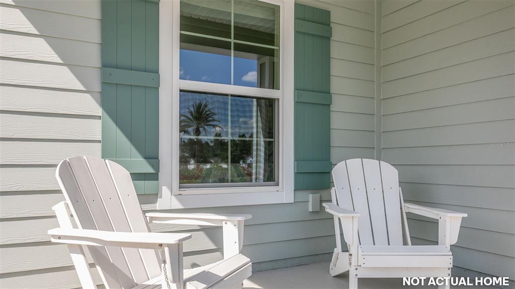 Two white Adirondack chairs sit on a porch in front of a window with shutters — 12 MULLIGAN WAY, BUNNELL, FL