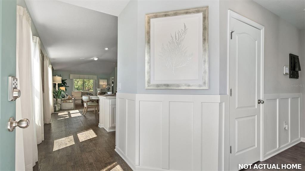 A foyer with white wainscoting leads into an open-concept living area with wood-look flooring — 12 MULLIGAN WAY, BUNNELL, FL