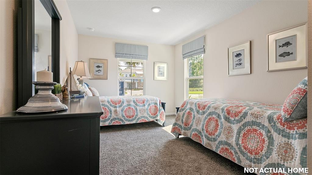 This bedroom features two twin beds with patterned quilts, carpeted floors, and two windows — 12 MULLIGAN WAY, BUNNELL, FL