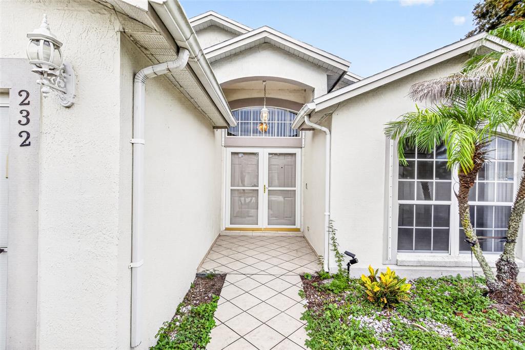 The exterior of a house features a tiled entryway, double front doors, and a palm tree — 232 KINGS POND AVENUE, WINTER HAVEN, FL