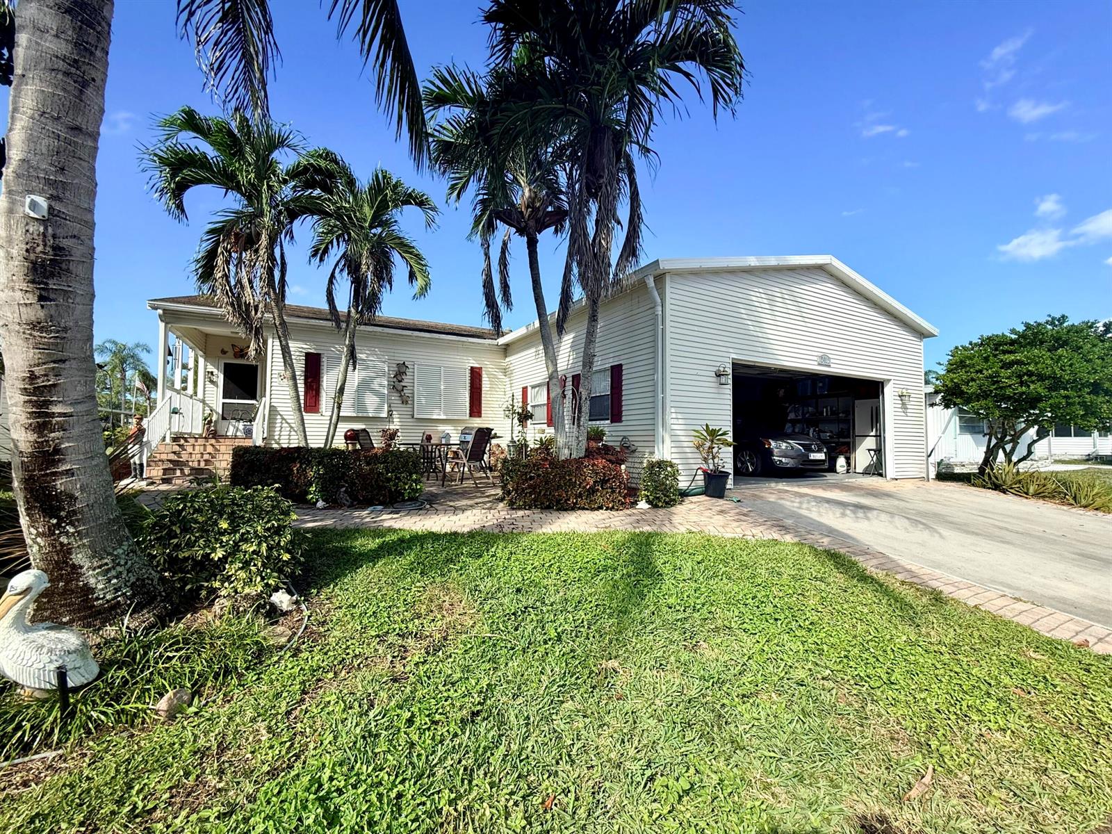 A single-story house with white siding, a two-car garage, and palm trees in the front — 6403 Birch Lane, Lantana FL 33462, LANTANA, FL