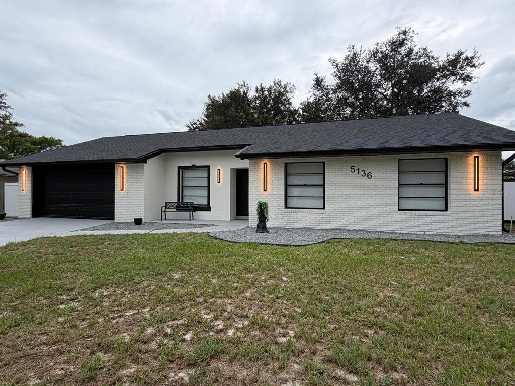A single-story house with white brick, a black roof, and black-framed windows — 5136 NADINE STREET, ORLANDO, FL