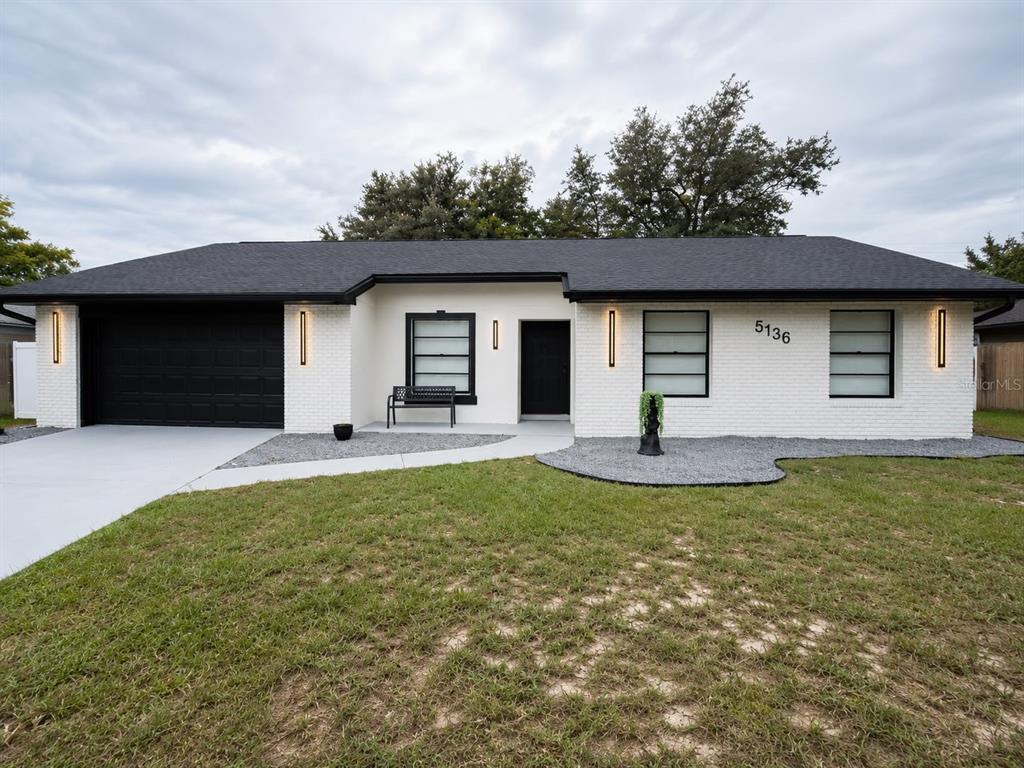 A single-story house with white brick walls, a black roof, and a black garage door — 5136 NADINE STREET, ORLANDO, FL