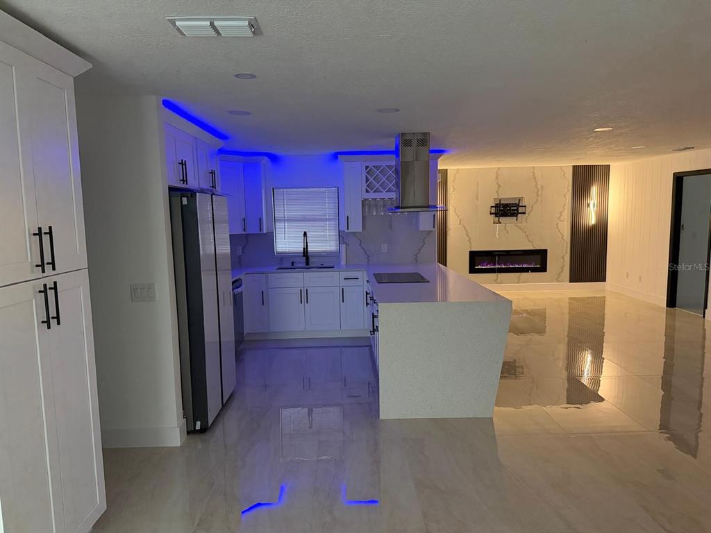 A modern kitchen with white cabinetry, a waterfall island, and blue accent lighting — 5136 NADINE STREET, ORLANDO, FL