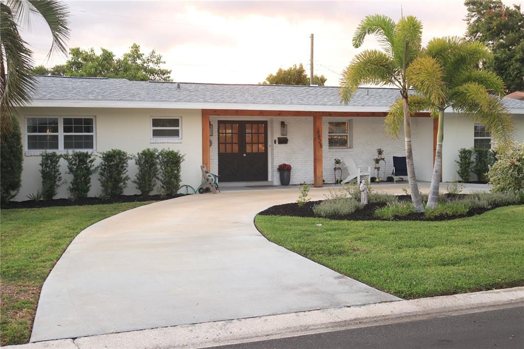 A single-story house with a white exterior, dark double front doors, and a concrete driveway — 6825 11TH AVENUE N, ST PETERSBURG, FL