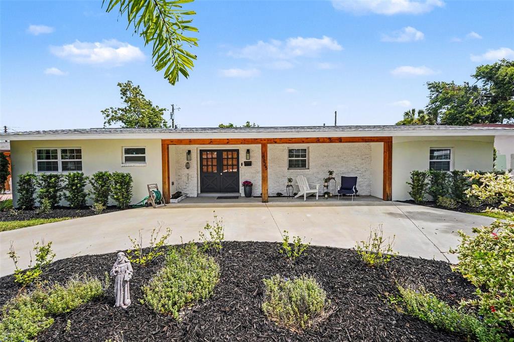 A single-story house with a white exterior, dark double doors, and a concrete driveway — 6825 11TH AVENUE N, ST PETERSBURG, FL