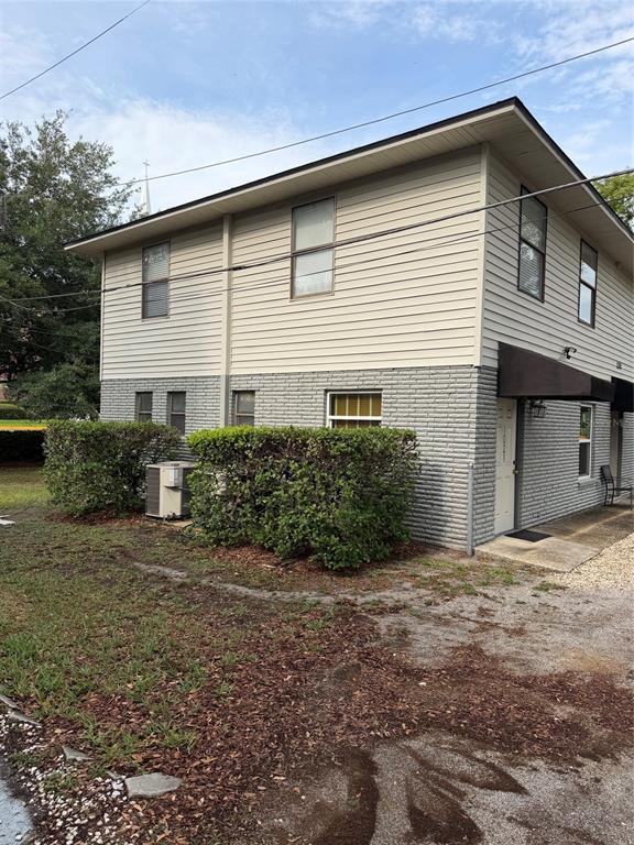 A two-story building with beige horizontal siding and a gray brick lower level — 131 W BROADWAY STREET UNIT 1001, OVIEDO, FL