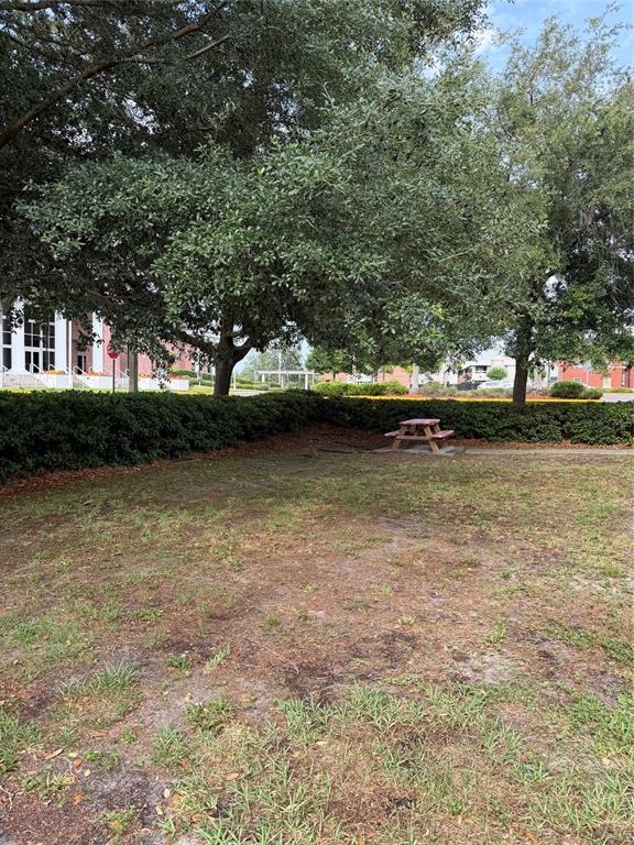 A small wooden picnic table sits on a patch of grass near a hedge — 131 W BROADWAY STREET UNIT 1001, OVIEDO, FL