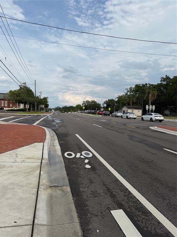 A paved road with a bike lane marking stretches toward a line of parked cars — 131 W BROADWAY STREET UNIT 1001, OVIEDO, FL