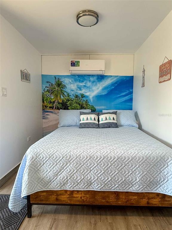 A bedroom features a bed with a blue quilt against a beach-themed wall mural — 324 CAMINO SOL, VIEQUES, PR