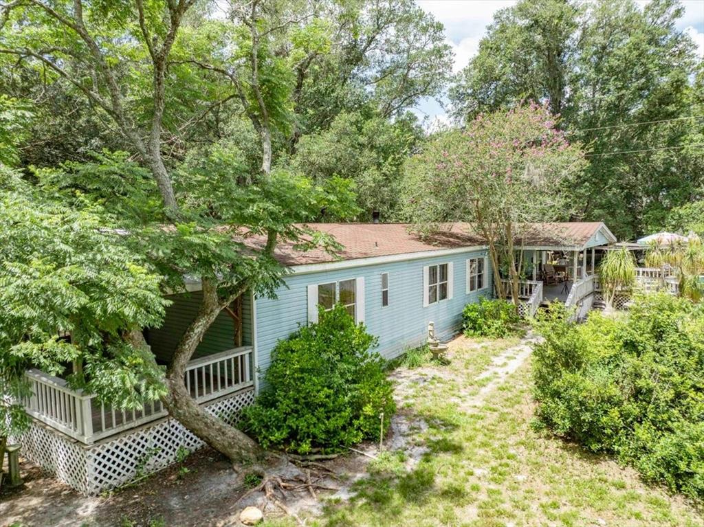 A light blue mobile home with a wooden porch sits among trees and lush landscaping — 2202 D R BRYANT RD, LAKELAND, FL