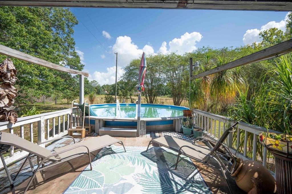 A wooden deck features two lounge chairs, a patterned rug, and an above-ground swimming pool — 2202 D R BRYANT RD, LAKELAND, FL
