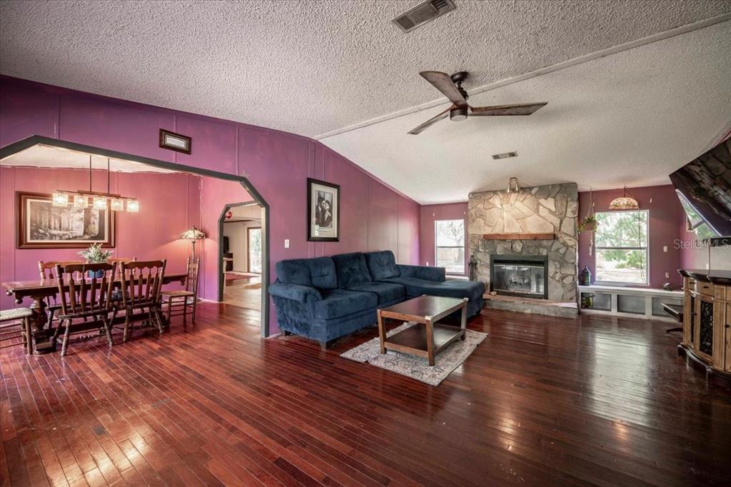A living room with purple walls, a stone fireplace, and dark wood flooring — 2202 D R BRYANT RD, LAKELAND, FL