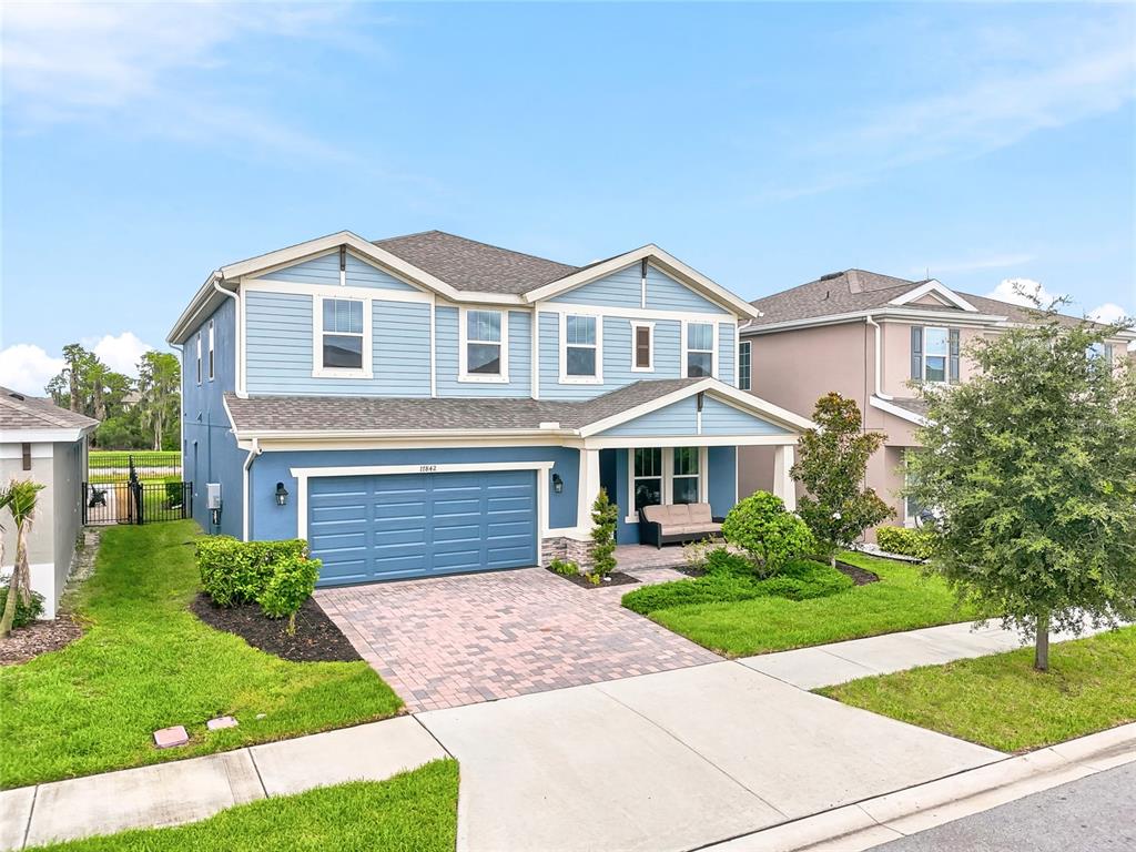 A two-story blue house features a two-car garage, a covered porch, and a paved driveway — 17842 EVERLONG DRIVE, LAND O LAKES, FL