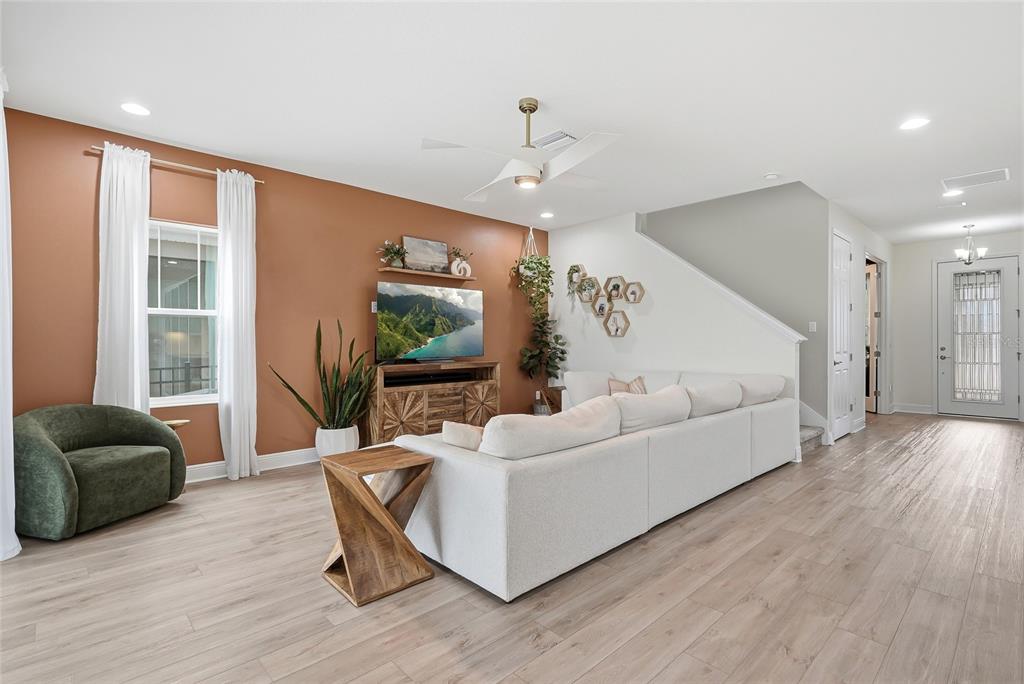A living room features a terracotta accent wall, white sectional sofa, and light wood flooring — 17842 EVERLONG DRIVE, LAND O LAKES, FL