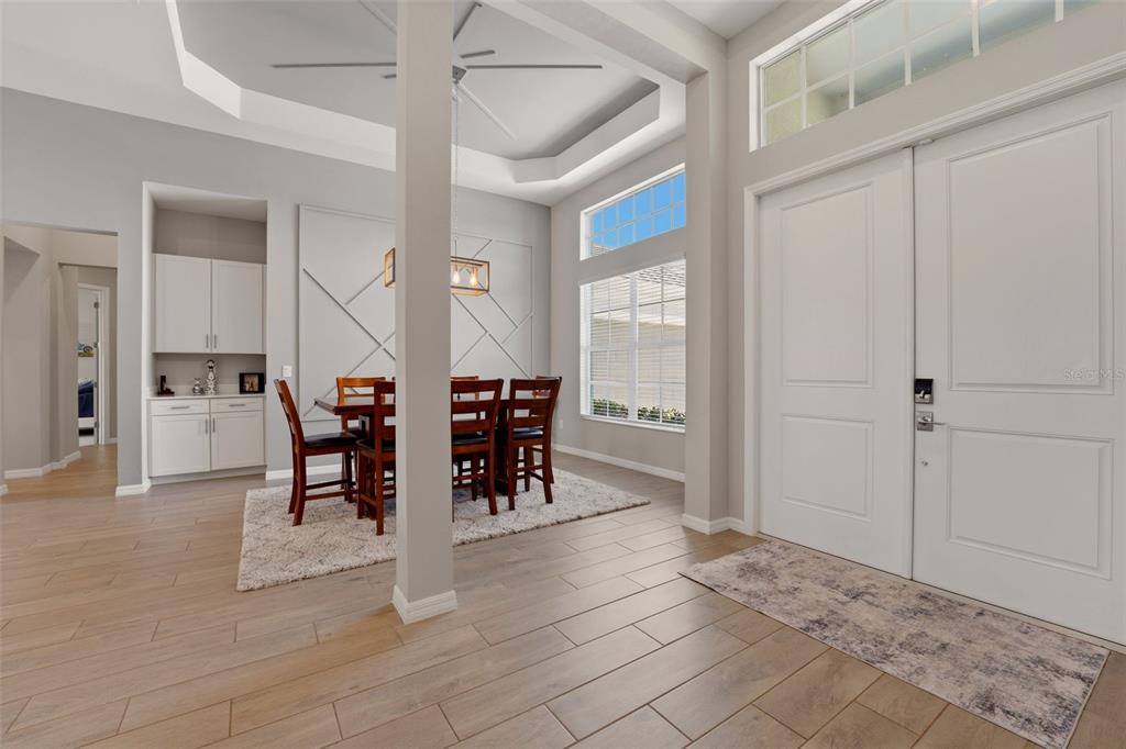 A dining area with a tray ceiling and wood-look tile floors near an entryway — 12299 WELLEN GOLF STREET, VENICE, FL