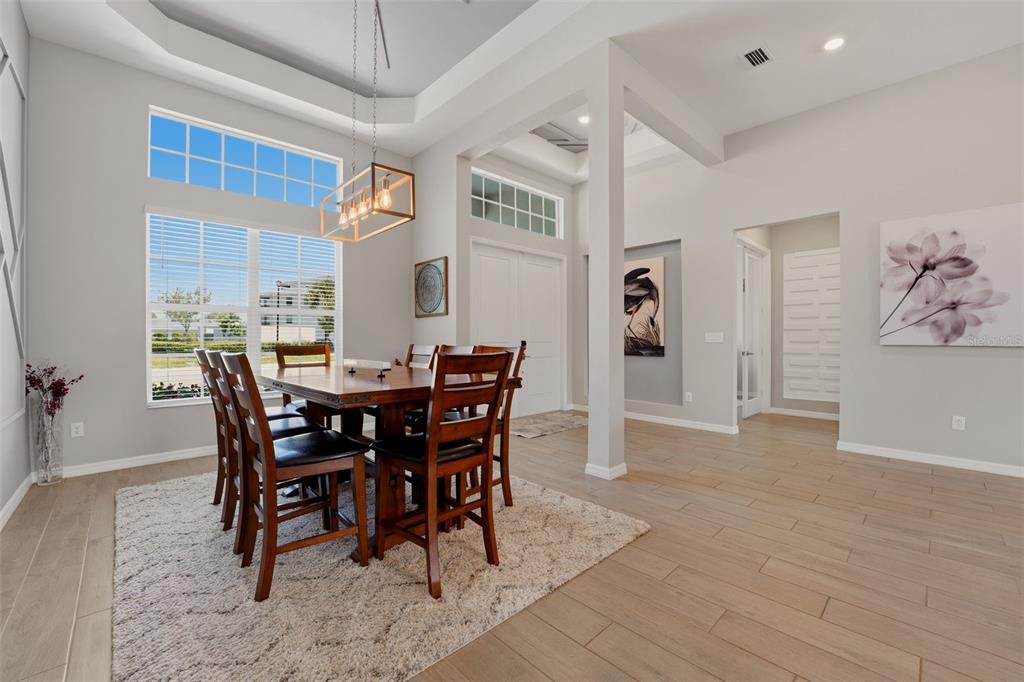 A dining room with a wooden table, chairs, a rug, and a modern light fixture — 12299 WELLEN GOLF STREET, VENICE, FL