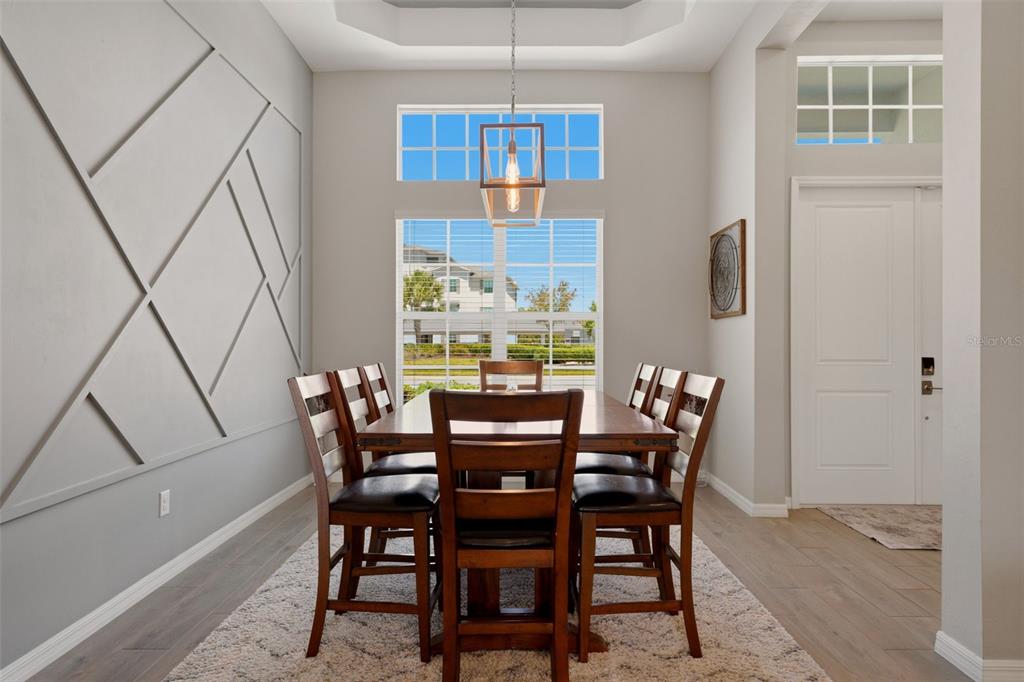 A dining room features a geometric accent wall, a wooden table, and a pendant light — 12299 WELLEN GOLF STREET, VENICE, FL