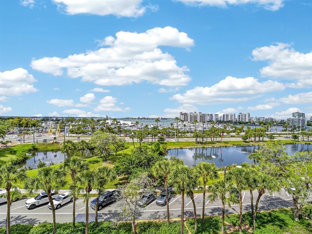 An elevated view of a parking lot, a pond, palm trees, and a distant marina — 1255 N GULFSTREAM AVENUE UNIT 507, SARASOTA, FL