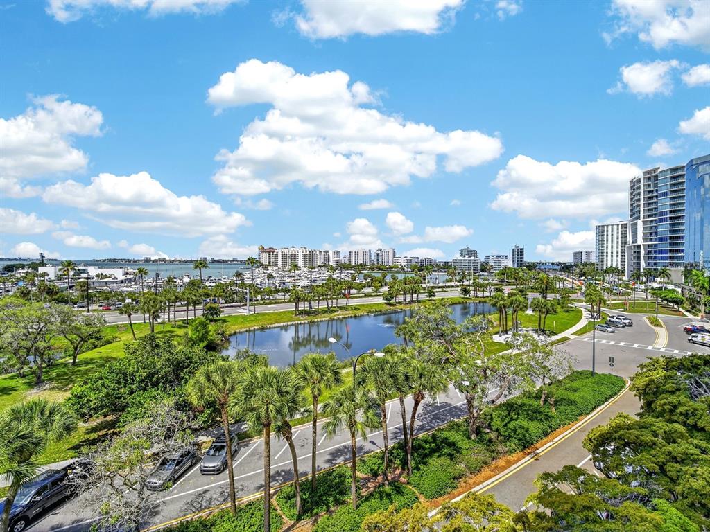 An elevated view of a pond, palm trees, a marina, and high-rise buildings under clouds — 1255 N GULFSTREAM AVENUE UNIT 507, SARASOTA, FL