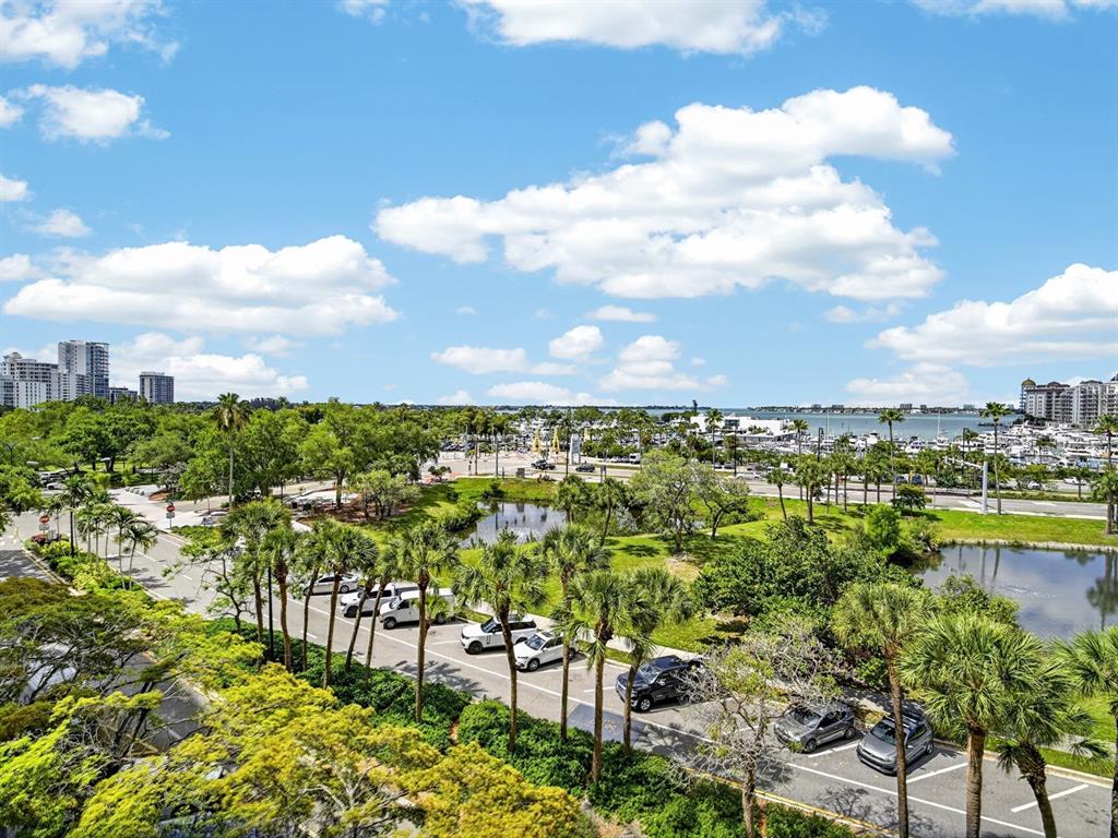 An elevated view of a parking lot, palm trees, a small pond, and a marina — 1255 N GULFSTREAM AVENUE UNIT 507, SARASOTA, FL