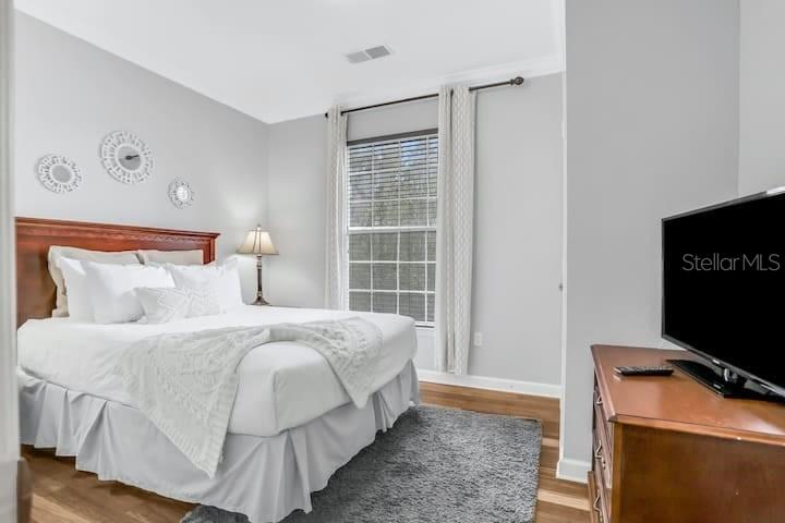 A bedroom features a wooden bed frame, a television on a dresser, and a window — 1301 TUSCAN TERRACE UNIT 9308, DAVENPORT, FL