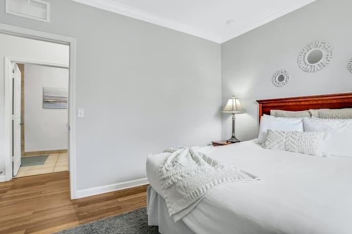A bedroom features a bed with white bedding, a wooden headboard, and an adjacent bathroom — 1301 TUSCAN TERRACE UNIT 9308, DAVENPORT, FL
