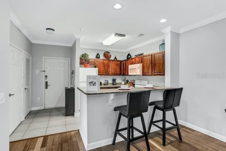 A kitchen with wood cabinets and a breakfast bar featuring two black stools — 1301 TUSCAN TERRACE UNIT 9308, DAVENPORT, FL