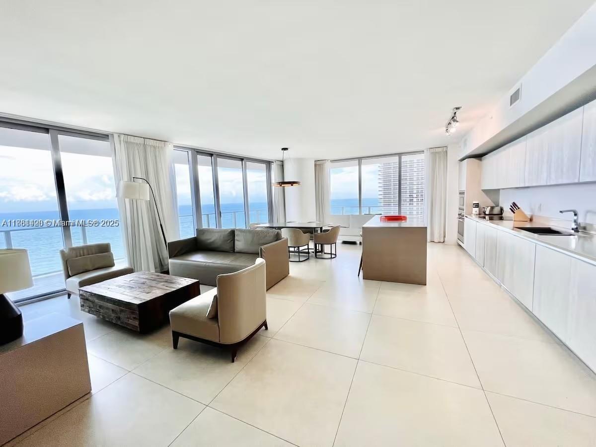 This open-concept living and kitchen area features floor-to-ceiling windows with ocean views and tile flooring — 4111 S Ocean Dr # 1801, Hollywood FL 33019, HOLLYWOOD, FL